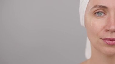 Güzel bir kadın yüz serumu uyguluyor. Yüzünde pipet var. Stüdyoda, gri arka planda. Yüz bakımı için estetik prosedürler. Makyaj hazırlığı. Yarım yüz portresi. Arkaplan. Boşluğu kopyala.
