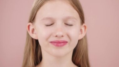 Yüzüne toner püskürten güzel bir kızın portresi. Gençler için cilt bakım ürünü konsepti. Kişisel bakım ve güzellik rutini. Stüdyoda pembe arka planda mavi gözlü sarışın kız..