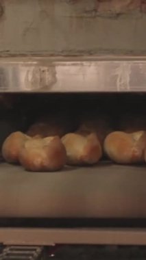 Dikey video: Bir taşıyıcı, geleneksel pişirme ve otantik mutfak işçiliği eğilimini yansıtan, küçük bir Türk fırınındaki fırından taze altın ekmeği kaldırdı. 