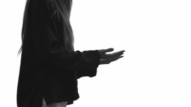 Tanınmayan bir kadın beyaz arka planda dururken Tanrı 'ya dua ediyor ellerini kaldırıyor. İnancın, ruhsal bağlantının, minnettarlığın ve övgülerin sakin atmosferi. Uzayı kopyala Siyah ve beyaz.