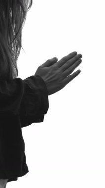 Dikey Ekran: Tanınmayan bir kadın yardım için ellerini sıkarak dua eder, beyaz arka planda durur. İnancın dingin atmosferi ve ruhsal bağlantı, ibadet ve övgü, umut. Siyah ve beyaz