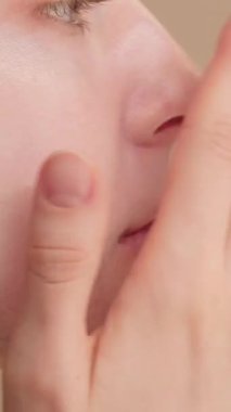 Stüdyonun arka planına makyaj yapan güzel bir kadının yakın plan çekimi. Güzellik anlayışı, doğal makyaj, Morinig cilt rutini, SPF güneş kremi, yüz kremi. 