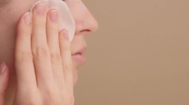 Cilt bakımı. Cotton Round ya da Cotton Pad kullanan güzel beyaz bir kadının yakın plan çekimleri. Stüdyonun arka planında yüzü temizliyor. Kişisel bakım, günlük rutin. Dermatoloji. Sivilce tedavisi. Boşluğu kopyala