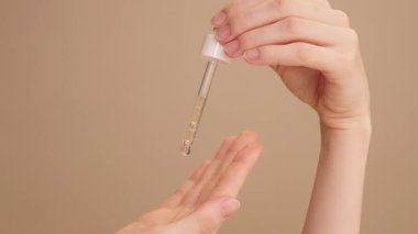 Estetik kadın elleri izole edilmiş bej arka plan tutucu, yaşlanma önleyici yüz serumu, destekleyici, yağ, saç jölesi. Cilt bakımı, nemlendirici, C vitamini, kırışıklık önleyici, yüz gerdirme, sivilce serumu.