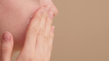 Sabah güzellik rutini. Genç kadın cilt bakımı ve makyaj hazırlama rutininin bir parçası olarak besleyici yüz kremi sürüyor. Kusursuz ve ışıl ışıl bir makyaj uygulaması için cildi sulandırır ve yumuşatır..