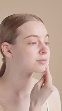 Genç bir kadın, sabah cilt bakımı sırasında yüzünü pamukla nazikçe temizliyor. Minimalist kişisel bakım ritüeli, sağlıklı ve ışıl ışıl bir cilt. Evde yüz bakımı var..