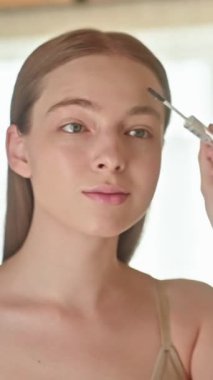 Kaşlarını jöle ya da balmumuyla şekillendiren genç bir kadın. Güzellik rutini tımar ve doğal kaşları yerleştirmeye odaklıdır. Kaş bakımı ve kaş şekillendirme ürünlerini desteklemek için ideal..