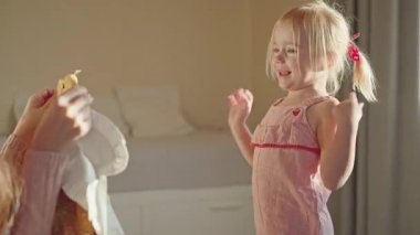 Mutlu genç anne kızına bir hediye vererek sevgisini ve ilgisini ifade ediyor. Küçük kız yeni elbiseye şaşırdı, annesine sarıldı. Şefkatli bir aile anı. Duygusal bir bağ.. 