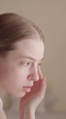 Genç bir kadın aynaya bakar, yüz derisinin durumunu kontrol eder, ve... Zombi Kadın endişeli bir şekilde yüzüne dokunuyor. Cilt sorunları, yaşlanma, sivilce. Cilt bakımı ürünleri, cilt bakımı