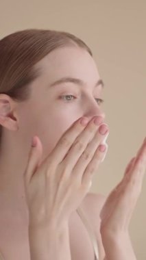 VERTICAL VIDEO Kadın ve yüz yıkama, günlük cilt rutini. Köpük temizleyici süren genç bir kız. Sabah güzellik rutini, temiz ve estetik. Yüz temizleme köpük reklamı konsepti