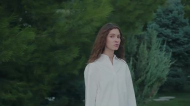 Endişeli genç kadın kameraya bakıyor, stresli, endişeli, yalnızlık, güvensizlik, sorunlu ilişki, depresyon, üzüntü hissediyor. Genç kız ağaçların arasında yapayalnız.