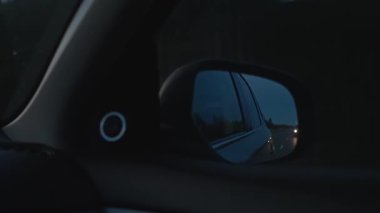 Otoyoldaki bir arabanın dikiz aynasından bak. Gece gezisi, alacakaranlık. Avrupa, Finlandiya 'ya yolculuk. Seyahat, turizm.