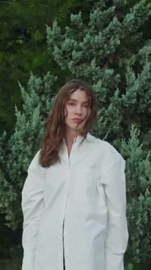 Dışarıdaki kameraya bakarak poz veren modacı mankeni. Sakin, genç, beyaz bir kızın çarpıcı yüzü. Esmer kadın güzellik portresi. Güzellik videosu konsepti, saç stili, gençlik kültürü, kişisel bakım