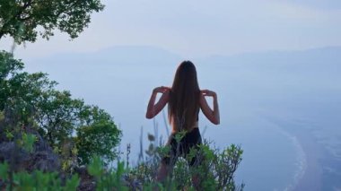 Sabahları kollarını ve omuzlarını dışarı uzatan genç bir kadının arka görüntüsü. Atletik kadın doğada ısınıyor. Zindelik, sağlık, esneklik ve sağlıklı yaşam tarzı kavramı.