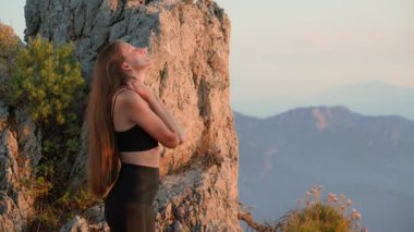 Gün batımında, boynu dışarıda spor yapan genç ve zinde bir kadın. Spor giyimli bayan sporcu sağlıklı yaşam tarzı için ısınma egzersizi yapıyor. Zihinsel sağlık için dışarıda egzersiz, stres atağı.