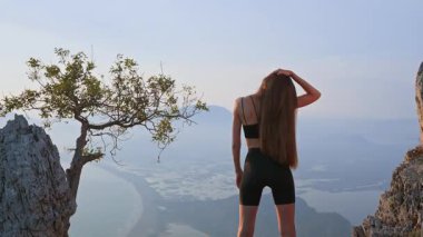 Gün batımında boynunu dışarı uzatan atletik kadının arka görüntüsü. Sportif genç yetişkin ısınıyor ve kişisel bakım için dinleniyor. Duruş, esneklik, sağIık ve sağlık için yaz çalışması.