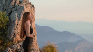 Atletik kadın gün batımında dışarıda omuz ısıtma gösterisi yapıyor. Sportif bir kız ve doğada bir akşam sporu. Güç, denge ve hareket kontrolü kavramı. Eklem ve kas hasarının önlenmesi