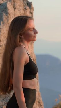 Gün batımında doğada boyun esnetme egzersizleri yapan zinde bir kadın. Duruş, kas gevşeme ve esneklik için açık hava ısınma rutini. Sağlıklı yaşam tarzı, spor giyim sektöründe kişisel bakım..