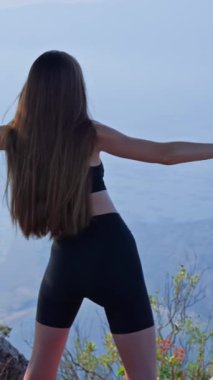 Kollarını uzatan ve doğada ısınan genç atletik bir kadının görüntüsü. Açık hava hareketlilik eğitimi, dışarıda çalışma, dinlenme, farkındalık, fitness, sağlıklı yaşam tarzı kavramı