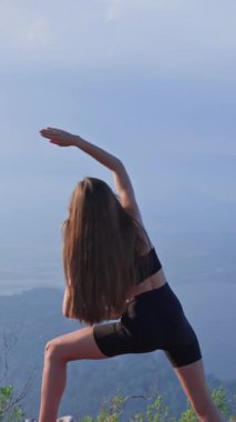 Spor giyim bölümündeki kadın gün batımında yan yana gerinme gösterisi yapıyor. Gerginliği azaltmak ve omurga ve gövde esnekliğini arttırmak için akşam ısınması. Sakinlik, denge ve hareketlilik kavramı.