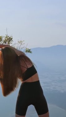 Gün batımında kollarını yan tarafa doğru uzatan sportif bir kız. Vücudun yan tarafını açmak ve esnekliği arttırmak için akşam egzersizi. Özgürlük kavramı, akış ve sakinlik gücü.