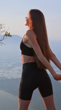 Sıcak akşam ışığında göğsünü ve kollarını dışarıda geren sportif bir kız var. Sağlıklı bir yaşam tarzının parçası olarak açıklık, nefes ve nazik vücut hareketliliği kavramı. Üst vücut hareketliliği.