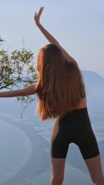 Gün batımında omuz hareketi talimi yapan atletik genç bayan. Eklem menzilini geliştirmek ve yaralanmayı önlemek için açık hava ısınması. Kontrol, güç ve sağlıklı hareket kavramı.