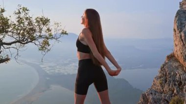 Sıcak akşam ışığında göğsünü ve kollarını dışarı açan sportif kız. Sağlıklı bir yaşam tarzının parçası olarak açıklık, nefes ve nazik vücut hareketliliği kavramı. Üst vücut hareketliliği.