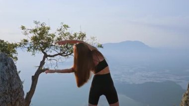 Gün batımında kollarını açık havaya doğru uzatan sportif kız. Vücudun yan tarafını açmak ve esnekliği arttırmak için akşam egzersizi. Özgürlük kavramı, akış ve sakinlik gücü.