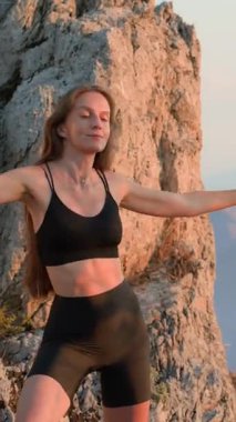 Spor giysili formda bir kadın gün batımı ısınma egzersizi sırasında kollarını açıp yavaşça yan yana sallanıyor. Rahatlama, hareketlilik ve bilinçli vücut hareketi kavramı.