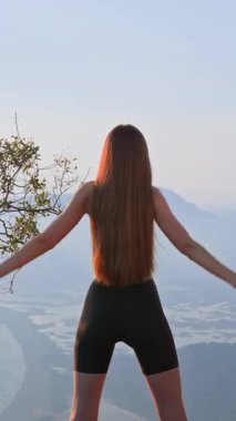 Spor giyim bölümündeki kadın gün batımında, arka planda omuz hareketlerinde yavaş hareket ediyor. Eklem esnekliği ve yaralanma önleme için hafif bir ısınma. Etkin yeniden canlandırma kavramı.