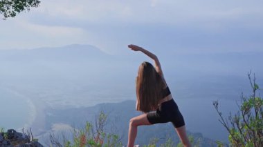 Spor giysili bir kadın gün batımında dışarıda dans ediyor. Gerginliği azaltmak ve omurga ve gövde esnekliğini arttırmak için akşam ısınması. Sakinlik, denge ve hareketlilik kavramı.