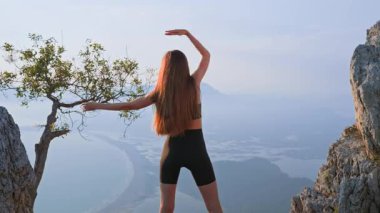 Atletik genç bayan gün batımında omuz hareketi talimi yapıyor. Eklem menzilini geliştirmek ve yaralanmayı önlemek için açık hava ısınması. Kontrol, güç ve sağlıklı hareket kavramı.