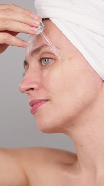 Cilt bakımı için hidratasyon serumu kullanan bir kadın parıltıyı arttırmak ve ten rengini değiştirmek için kozmetik ilaçlar kullanıyor. Stüdyoda mankenlik, yüz güzelliği için hyaluronik asidin cilt bakımı faydaları.