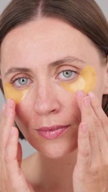 Dikey ekran: göz bantları, kadın ışıl ışıl yüzü güvenli bir şekilde kameraya bakıyor. Göz bandı uygulamaları. Cilt Bakımı Konsepti, Güzellik ve Kozmetik Ürünleri, Dermatoloji, Gençleştirme