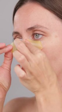 Dikey Ekran: Skincare, Göz bantları ve Esmer Kadın kozmetik için stüdyodalar. Işık efekti. Yüz bakımı ve kolajen parlaklık. Spa, estetik ve detoks. Gri arkaplandaki kişinin portresi.