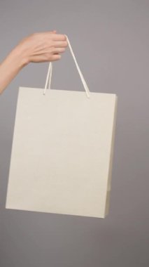 Alışveriş teslimat servisi. Gri arka planda kağıt torba. Ev için internet üzerinden bağlantısız alım. Kurye siparişi alır, müşteriye teslim eder. İndirimler, alışverişler, hediye reklamları. Hayırseverlik kavramı.