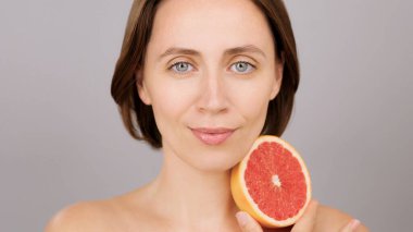 Greyfurt, gri arkaplan, doğal cilt bakımı, C vitamini ya da detoks içeren güzel beyaz kadın. Stüdyo portresi, çevre dostu kozmetik ürünler, organik beslenme