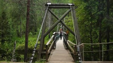 Ön manzara, genç bir turist kadını ya da Finlandiya 'da bir orman nehrinin üzerinde asılı bir köprüde yürüyen bir kadın yürüyüşçüyü gösteriyor. Seyahat, keşif, özgürlük ve doğa ile barışçıl bağ kavramı