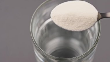 Bir bardak suya kolajen ya da protein tozu eklemeye yakın çekim. Beslenme takviyesi, sağlıklı yaşam tarzı, beslenme, güzellik bakımı ve çözünürlük ürünü hazırlığı kavramı. Sağlıklı olmak için yiyecek.