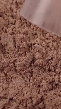 Dikey çekim. Çikolata protein tozuyla dolu bir kaşık çıkar. Spor besin takviyesi makro yakın çekim fitness, kişisel bakım, sağlıklı diyet, kas geliştirme iyileşme konsepti