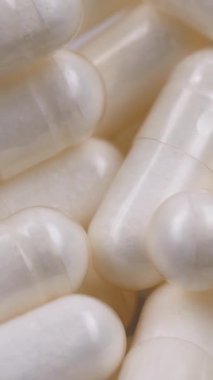 Beyaz kapsüllerin dönüşümlü makro çekimi, besin takviyeleri. Eczacılık üretimi. Tıp ve sağlık, tedavi, önleme ve sağlık kavramı. Haplar ve vitaminler makro