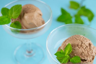 Masadaki bardakta nane yapraklı çikolatalı dondurma.