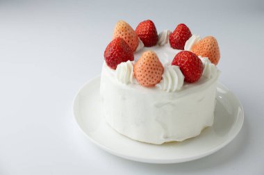 Beyaz arka planda beyaz tabakta çilekli pasta, seçici odak