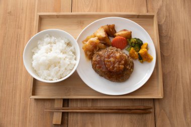 Birds-eye view of onion sauce Japanese hamburger steak on a white plate with sauteed vegetables