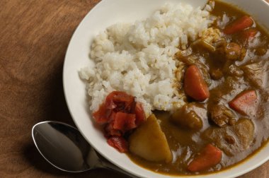 Japon domuz eti, beyaz bir tabakta servis edilir. Soya soslu dilimlenmiş turplar, ahşap bir masada, üst manzara..