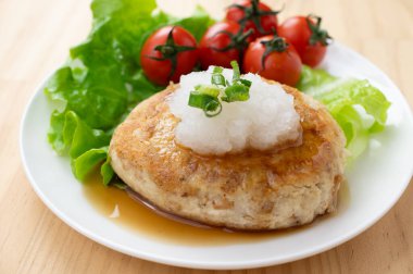 Bir tabak kiraz domatesli ve yeşil yapraklı Japon tofu burger bifteği ve üzerine de jöleli turp ve soya sosu.