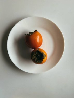 Minimalist beyaz bir tabakta sade bir arka planda taze hurma.