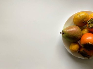 Beyaz bir tabakta, arka planda duran çeşitli taze meyveler.