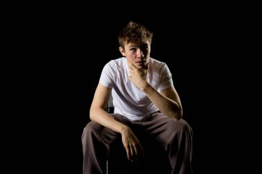 Portrait of a sitting emotional looking 17 year old teenage boy